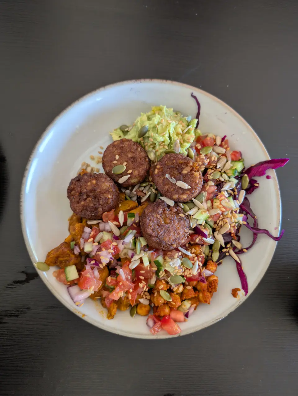 Bol de falafels dorés, avocat écrasé, chou rouge et graines