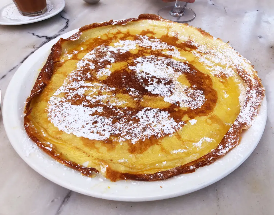 Crêpe au sucre glace servie sur une table de bistrot