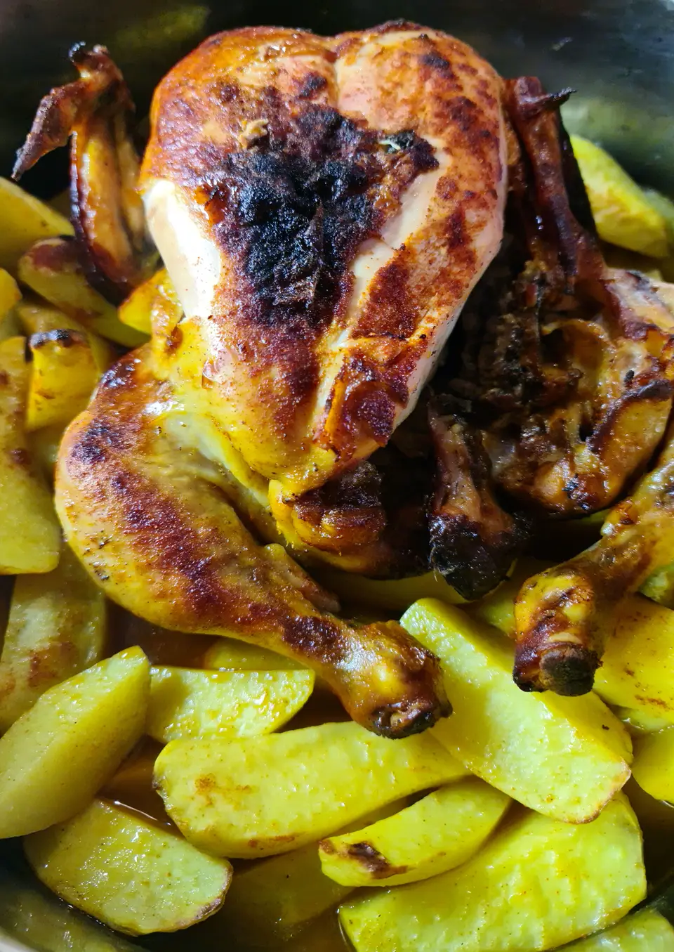 Poulet rôti doré entier, entouré de pommes de terre