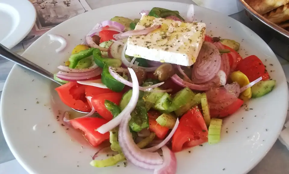 Salade grecque : tomates, concombre, poivron, oignon rouge, olives et une tranche de feta posée dessus