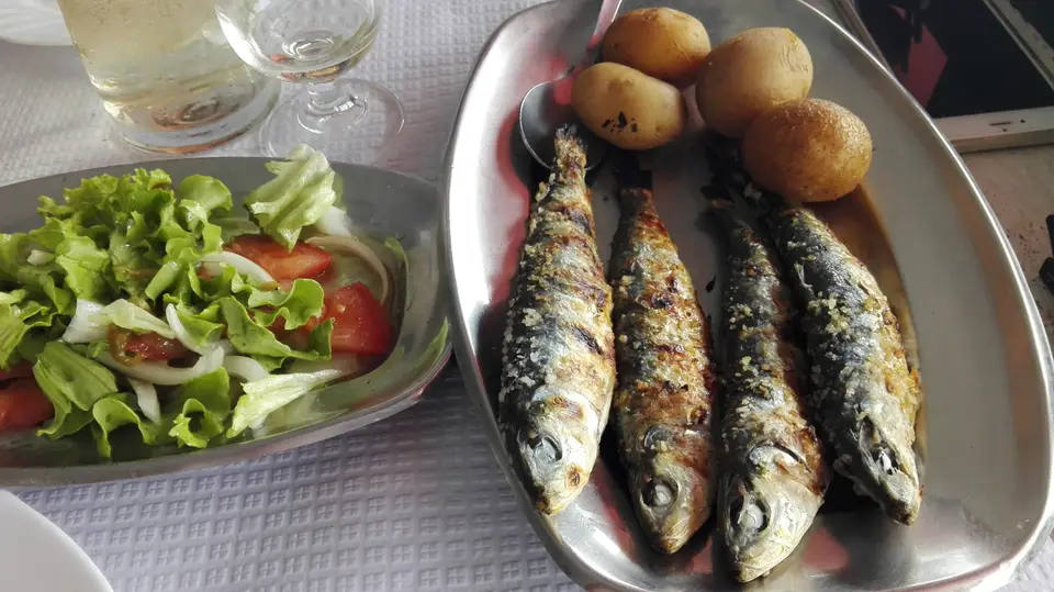Sardines grillées entières sur un plat, pommes de terre et salade