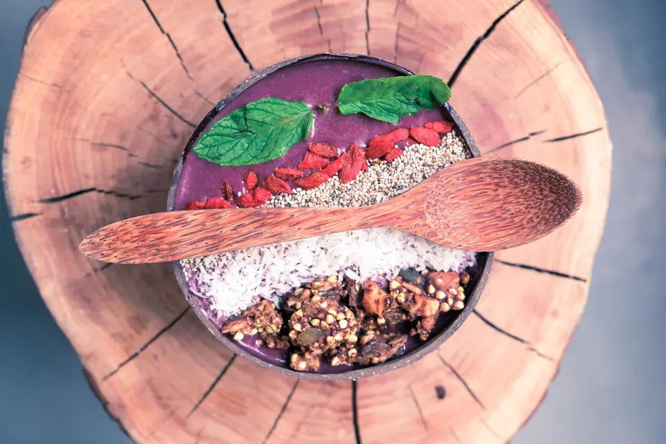 Smoothie bowl épais garni en bandes de granola, coco et fruits rouges