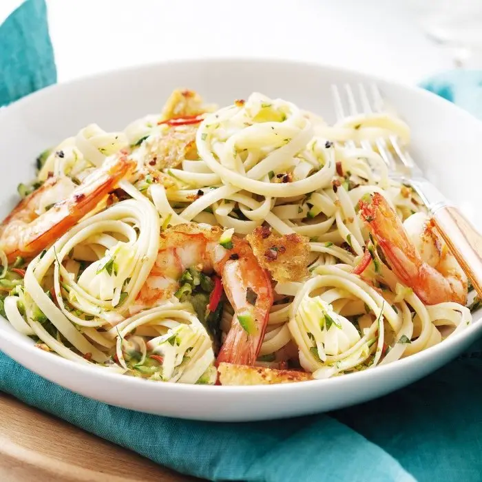 Linguine aux crevettes, tomates et basilic dans une assiette blanche