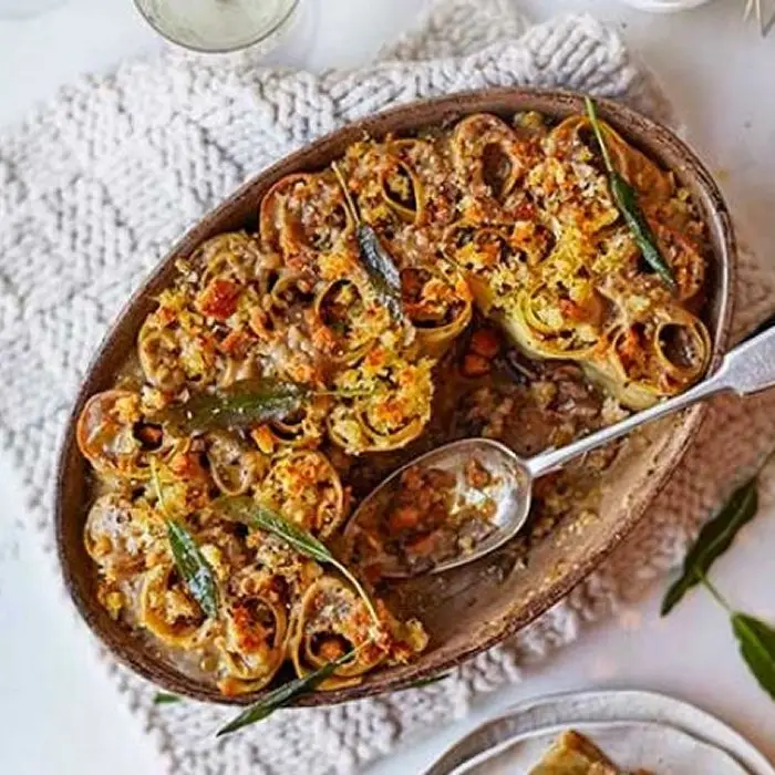 Rotolo de lasagnes roulées aux champignons dans un plat ovale, chapelure dorée et sauge