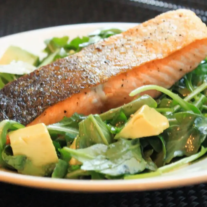 Pavé de saumon poêlé sur une salade d'avocat et de jeunes pousses