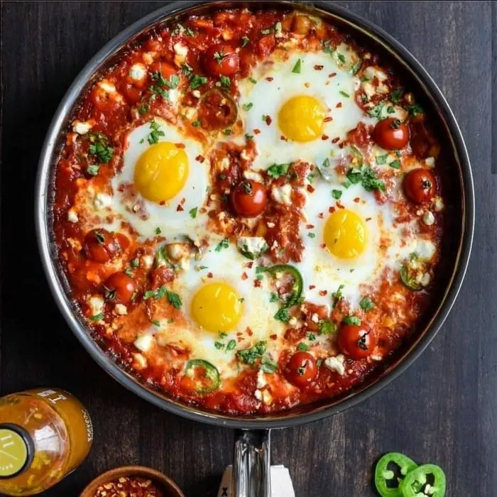 Shakshuka dans sa poêle : quatre œufs pochés dans une sauce tomate
