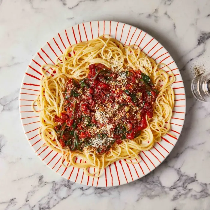 Spaghetti au chorizo, au poivron et au parmesan dans une assiette rayée