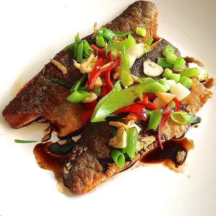 Filets de bar à la peau croustillante, couverts de gingembre, piment et oignon nouveau