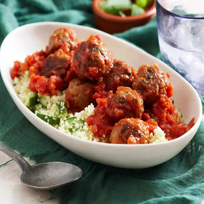 Boulettes d'agneau en sauce tomate sur de la semoule, menthe fraîche