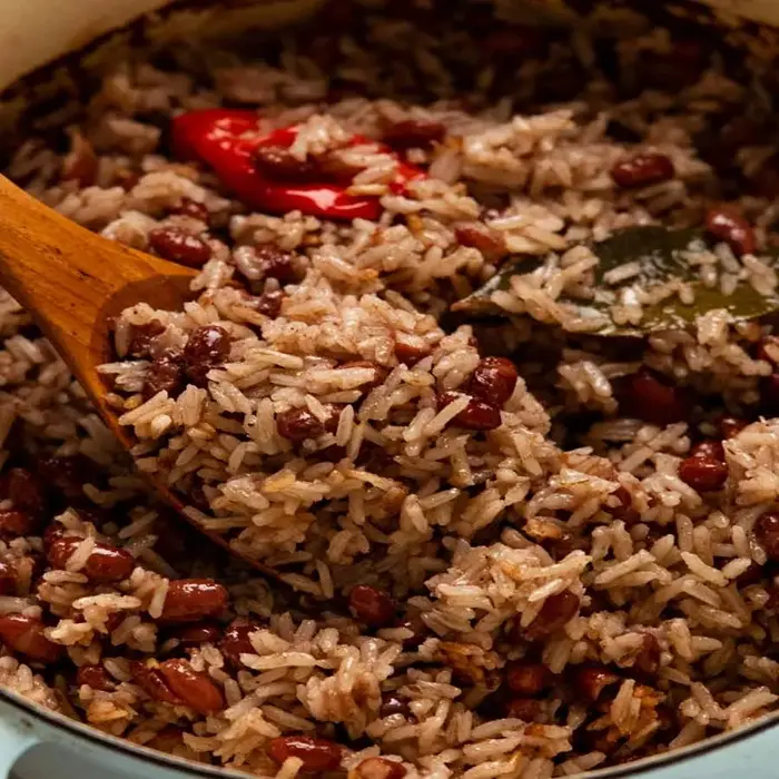 Riz aux haricots rouges dans une cocotte, piment rouge entier et cuillère en bois