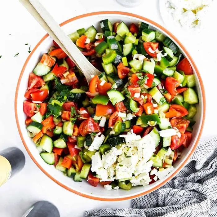 Salade de tomates, concombre et poivron en dés, feta émiettée, dans un saladier